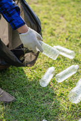 Hand picks up plastic bottles up close with young man volunteering to collect plastic bottles in...