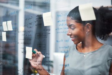 Happy, inspired and confident business woman brainstorming ideas, writing on transparent glass...