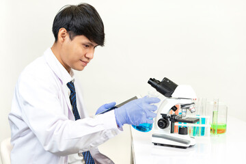 young attractive asian scientist working in chemical laboratory, searching data from tablet to do chemistry experiments with microscope