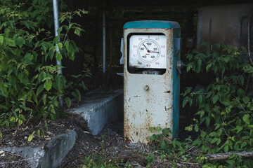 Old rusty abandoned gas station overgrown with grass and trees