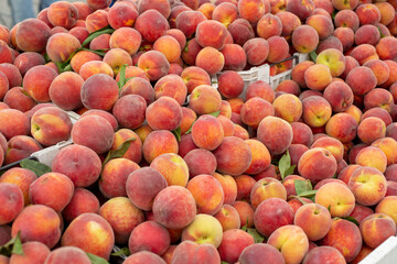 A view of a large pile of peaches, on display at a local farmers market.