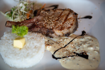 Grilled T-bone steak on a plate with rice.