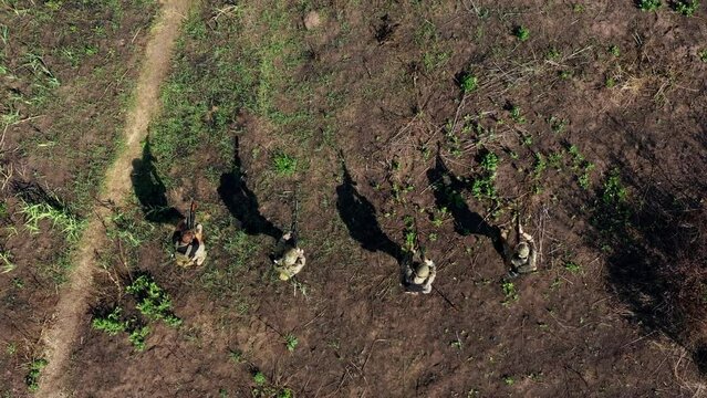 a group of servicemen in uniform with army training moves across the battlefield firing machine guns, special forces soldiers with firearms work as a team, shoot, fight and aim. War in Ukraine. drone 