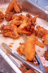A view of a large foil tray of deep fried chicken.