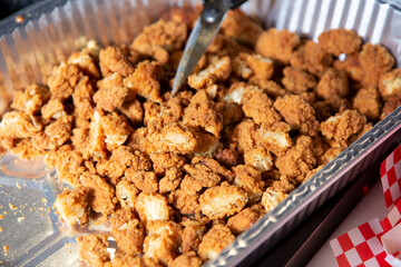 A view of a large aluminum tray full of deep fried chicken nuggets.