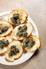 A top down view of a plate of escargot canapes.