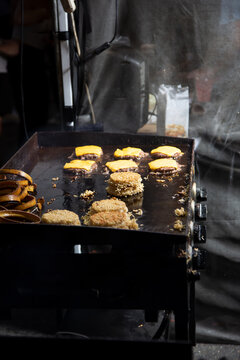 A View Of An Outdoor Griddle Cooking Up Ramen Burgers.