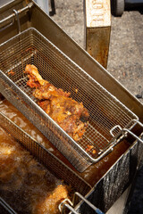 A view of a freshly made deep fried turkey leg, seen inside a deep fryer basket.
