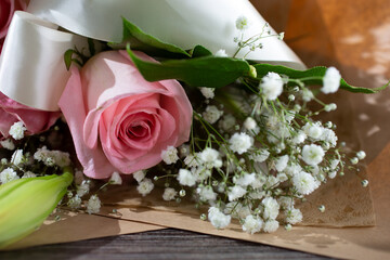 A closeup view of flower bouquet, featuring a pink rose and baby's breath.