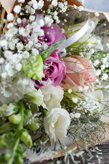 A closeup view of a floral bouquet, featuring roses and baby's breath. 