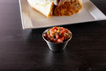 A view of a condiment cup of pico de gallo salsa.