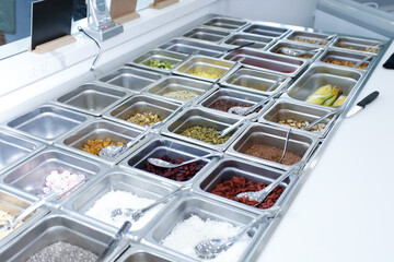 A view of a table full of ingredient bins, seen at a local acai restaurant.