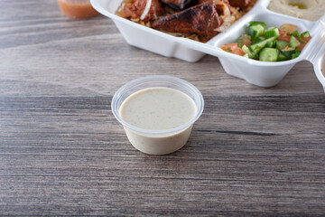 A view of a tahini sauce in a spoon shaped condiment cup.