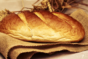a loaf of bread on burlap grain and ears of wheat