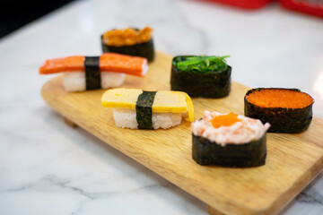Different types of sushi served on a wooden tray. Sushi