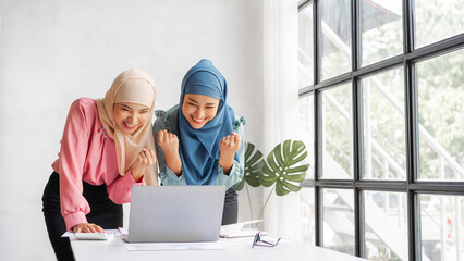 Young pretty female startup partners Islamic people raise their hands to congratulate when working with laptop, read a good email news, successful concept.