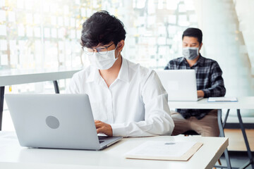 Business people with protective face masks are working in the office keeping a distance during COVID-19 pandemic . social distancing concept.