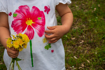 子供が摘んだタンポポの花束とシャツの中の花と蝶