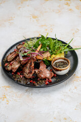 grilled meat loin in a plate with greens and grilled pineapple on a white background

