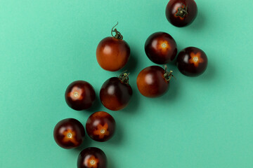 Black strawberry tomatoes on turquoise background. Top view.