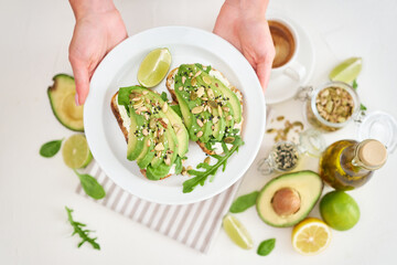 Freshly made Avocado and cream cheese toasts on a white ceramic plate and ingredients