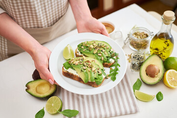 Freshly made Avocado and cream cheese toasts on a white ceramic plate and ingredients
