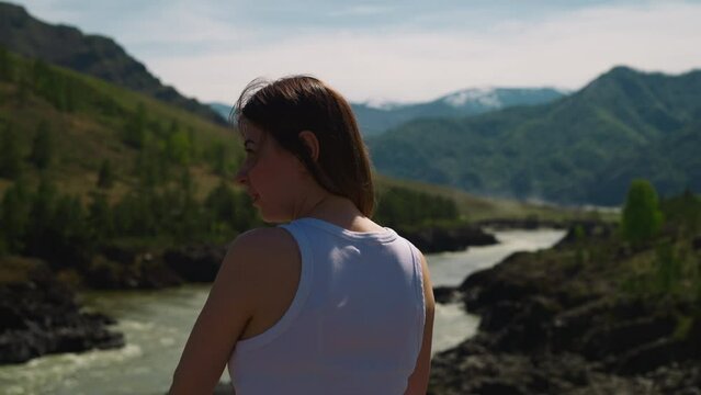 Lady looks at curved river and old mountains in valley