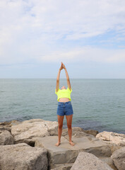 Fototapeta na wymiar girl in a shirt giving a gymnastic exercise on the rocks arching her back backwards