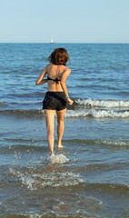 Fototapeta na wymiar slender athletic young girl running barefoot on the seashore