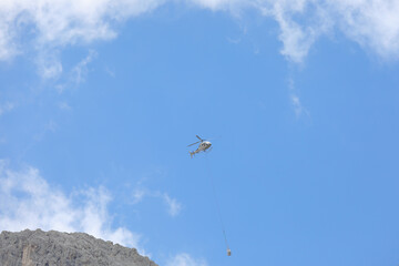 helicopter carrying material high in the mountains attached to a hook