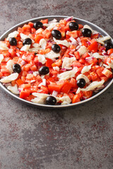 Catalan codfish salad as known as esqueixada, with cod, tomato onion and olive close-up in a plate on the table. Vertical