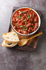 delicious Portuguese chicken gizzards moelas served with homemade bread close-up in a bowl on the wooden tray. Vertical top view from above
