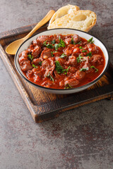 delicious Portuguese chicken gizzards moelas served with homemade bread close-up in a bowl on the wooden tray. Vertical
