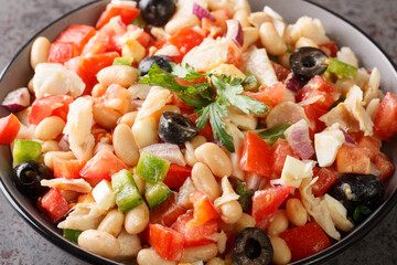 Mediterranean homemade cod salad with white beans, eggs and vegetables close-up in a bowl on the table. horizontal