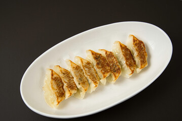 今日の晩ごはん　茶色い焦げ目がついて、おいしそうに焼かれたギョウザを白い皿に盛りつけた一皿　　