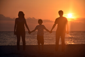 Fototapeta na wymiar Silhouette of family watching sunset at beach. Happy family enjoy on sea on summer vacation