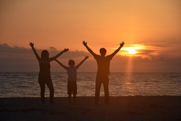 Fototapeta premium Silhouette of family watching sunset at beach. Happy family enjoy on sea on summer vacation