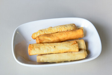 Turkish style meat stuffed filo dough borek served kol boregi. Cheese and minced pie are sliced on a marble background. Turkish name: Kol Boregi, kiymali, peynirli su boregi.