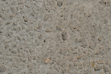 Fototapeta na wymiar The texture of a concrete wall interspersed with pebbles.