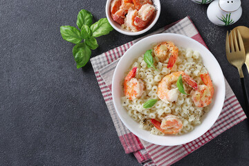 Italian ditalini pasta with shrimps and basil in a white bowl on dark background, Top view