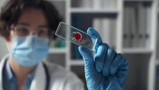 Woman doctor, laboratory assistant with drop of human red blood on slide glass for, blood group analysis, complete blood count (CBC) in hospital laboratory. Blood test in clinical laborator