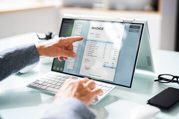 Businessperson Analyzing Invoice On Laptop