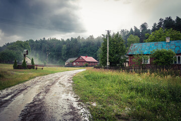 Beautiful rural landscape for a while after the storm has passed. Moody atmosphere of the Polish countryside. Country houses, a beautiful chapel, fog and a road flooded with rain