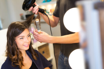 Naklejka premium Young woman getting new hairstyle from hairdresser in the modern hair salon