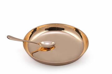 Bright shiny bronze spoon on round plate isolated on white background