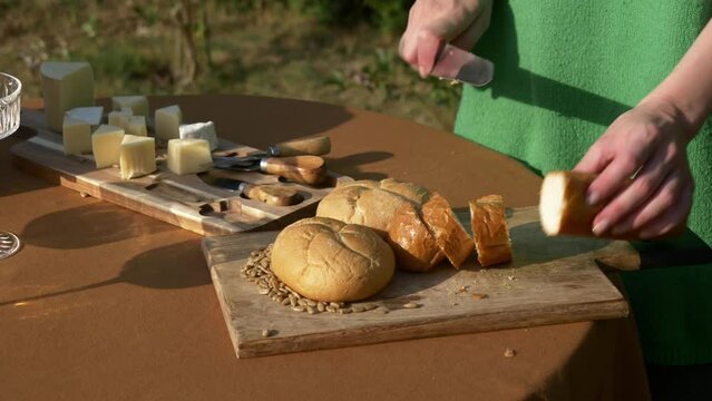Female in green sweater cut bread for snaks for outdoor party