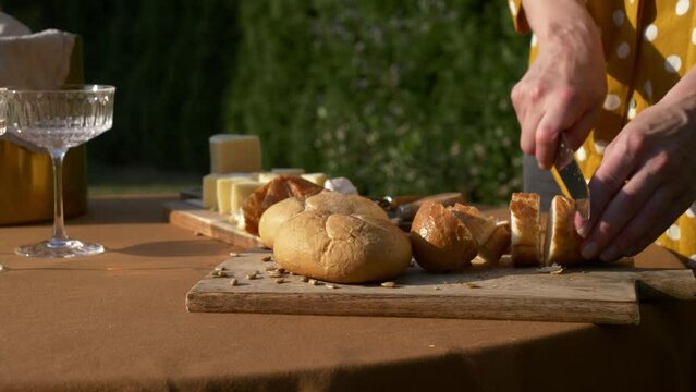 Female in polka dot shirt cut bread for snaks for outdoor party