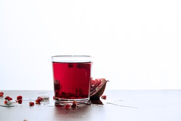 pomegranate juice in a low transparent glass, on a white background, natural pomegranate juice