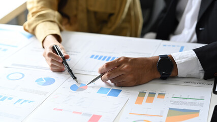 Two business colleagues are checking and analyzing financial data in corporate office. Cropped view
