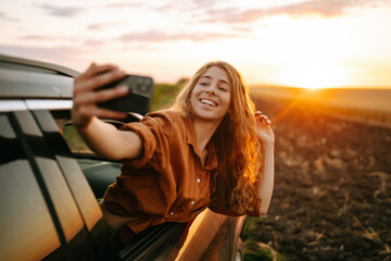 Selfie while traveling. Young woman takes a selfie in the car during a road trip. Lifestyle,...